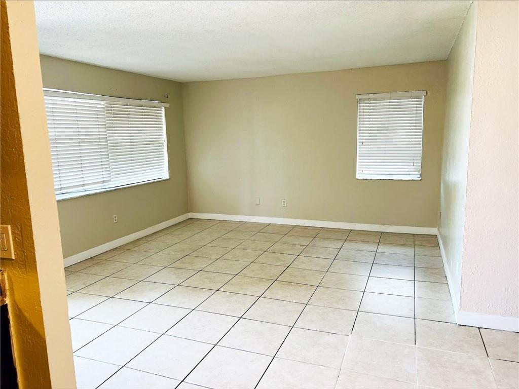 An empty room with beige walls, tile flooring, and two windows with white blinds — 400 NW 65th Avenue # 209, Margate FL 33063, MARGATE, FL