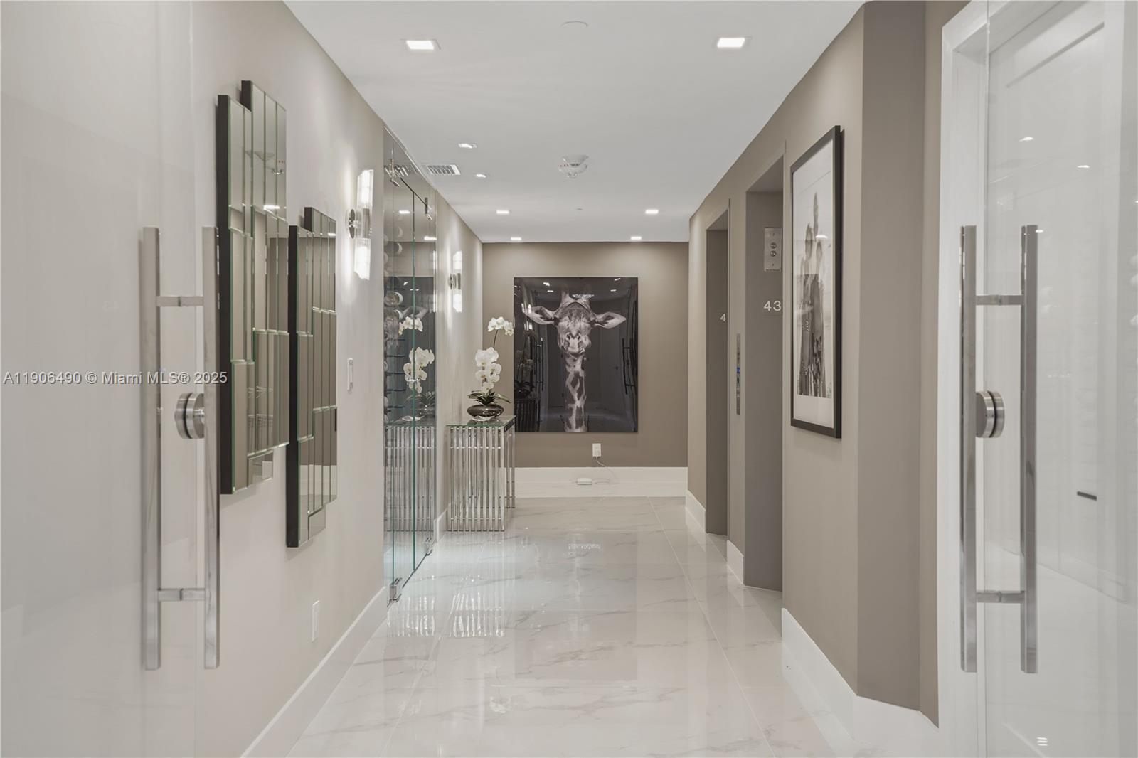 A modern hallway features marble flooring, a large giraffe portrait, and elevator access — 300 S Pointe Dr # 4306, Miami Beach FL 33139, MIAMI BEACH, FL