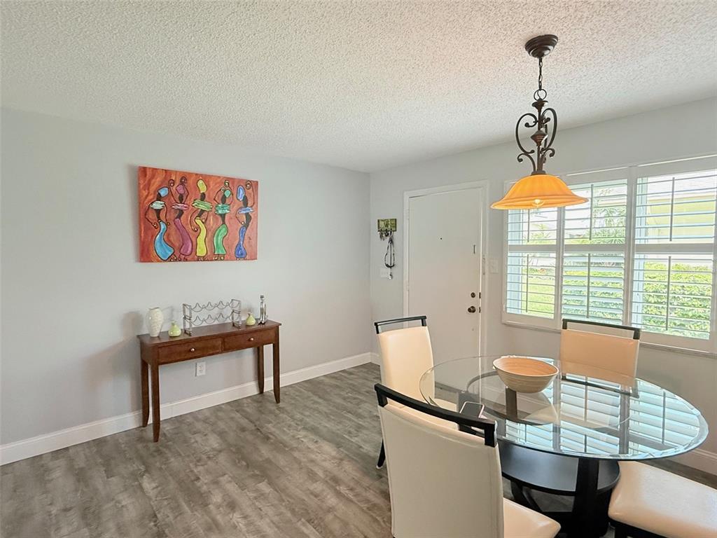 A dining room features a glass table, four chairs, a wooden console table, and artwork — 3357 38TH STREET S UNIT C, ST PETERSBURG, FL