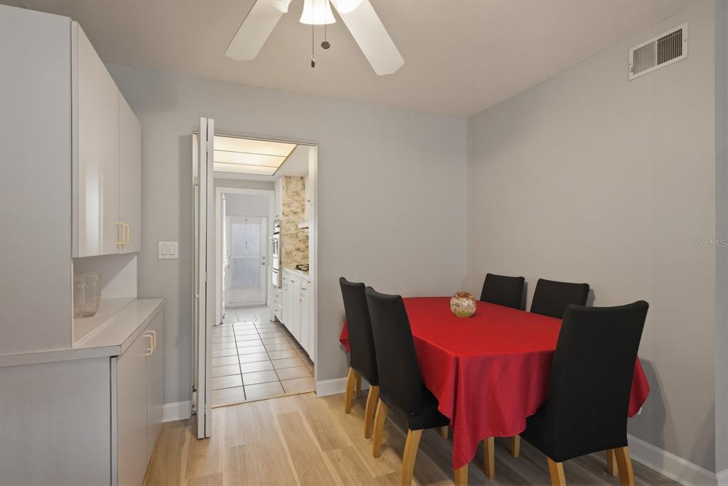 A dining room with a red-clothed table, black chairs, and a doorway to a kitchen — 2011 58TH AVENUE N UNIT 5, ST PETERSBURG, FL