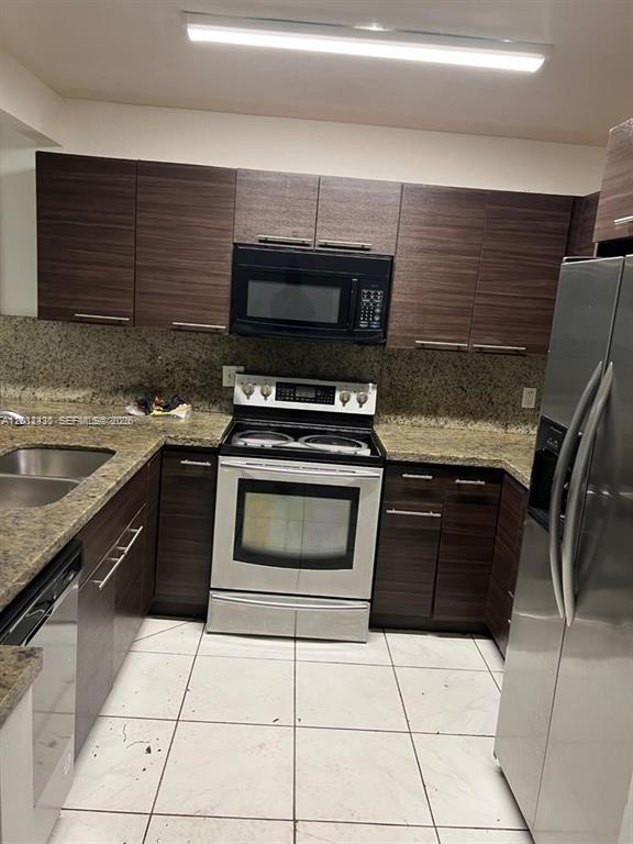 A kitchen features dark wood cabinets, stainless steel appliances, and speckled granite countertops — 5955 NW 25th Ct # 208, Sunrise FL 33313, SUNRISE, FL