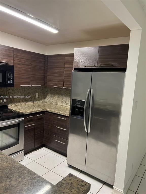 A kitchen features dark wood cabinets, granite countertops, and stainless steel appliances — 5955 NW 25th Ct # 208, Sunrise FL 33313, SUNRISE, FL