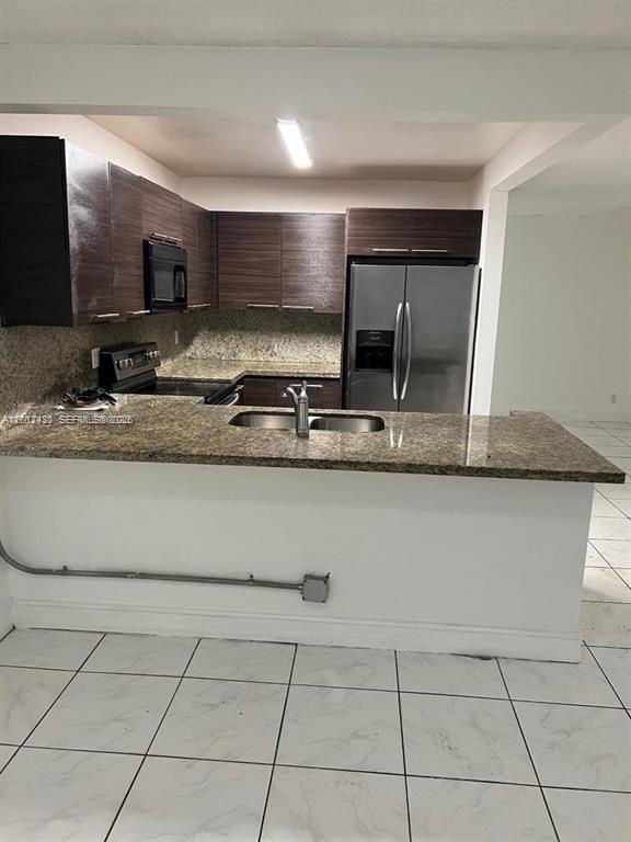 A kitchen features dark wood cabinets, granite countertops, stainless steel appliances, and white tile flooring — 5955 NW 25th Ct # 208, Sunrise FL 33313, SUNRISE, FL