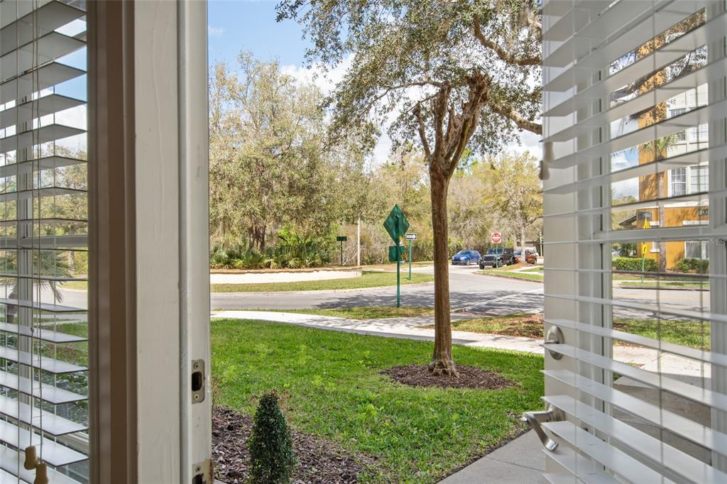 View from an open doorway looking out at a street, trees, and a residential building — 1410 CELEBRATION AVENUE UNIT #102, CELEBRATION, FL