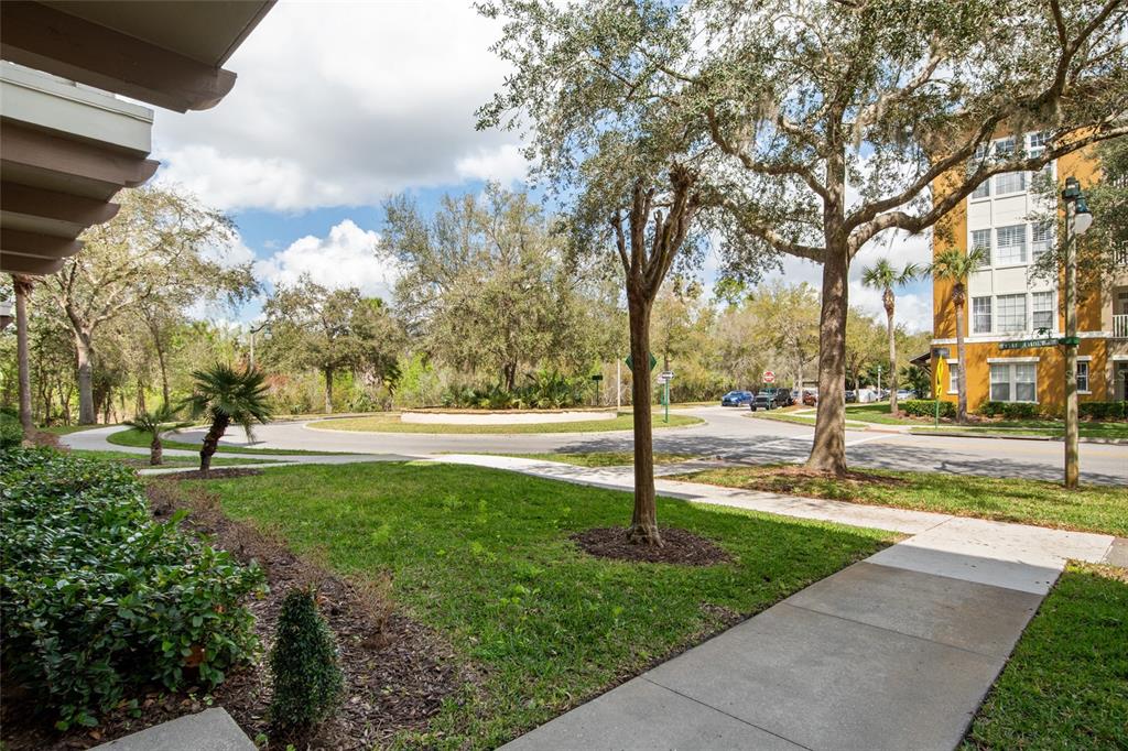 A view from a sidewalk looking toward a roundabout surrounded by trees and apartment buildings — 1410 CELEBRATION AVENUE UNIT #102, CELEBRATION, FL