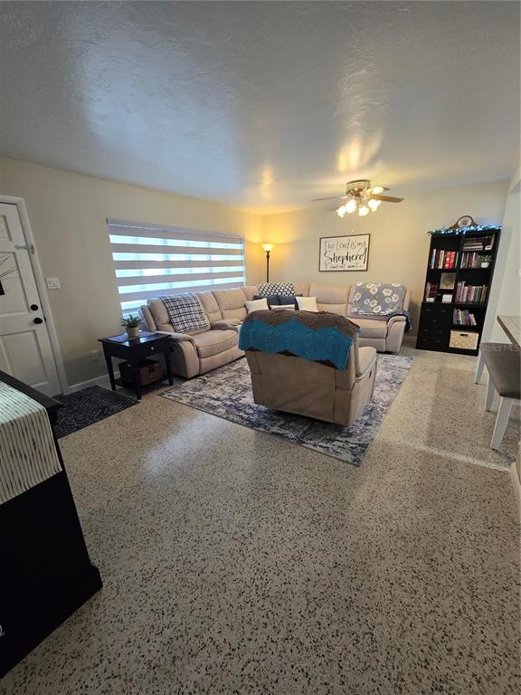 A living room features a sectional sofa, a recliner, a bookshelf, and speckled flooring — 3134 IRVING STREET, SARASOTA, FL