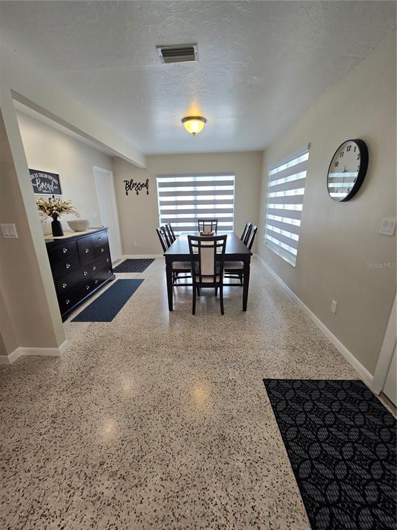 A dining room features a dark wood table, chairs, a matching sideboard, and terrazzo flooring — 3134 IRVING STREET, SARASOTA, FL