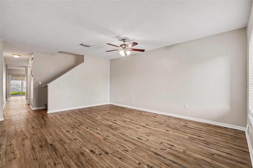 An empty living room features wood-look flooring, a ceiling fan, and a staircase — 2125 FLUORSHIRE DRIVE, BRANDON, FL