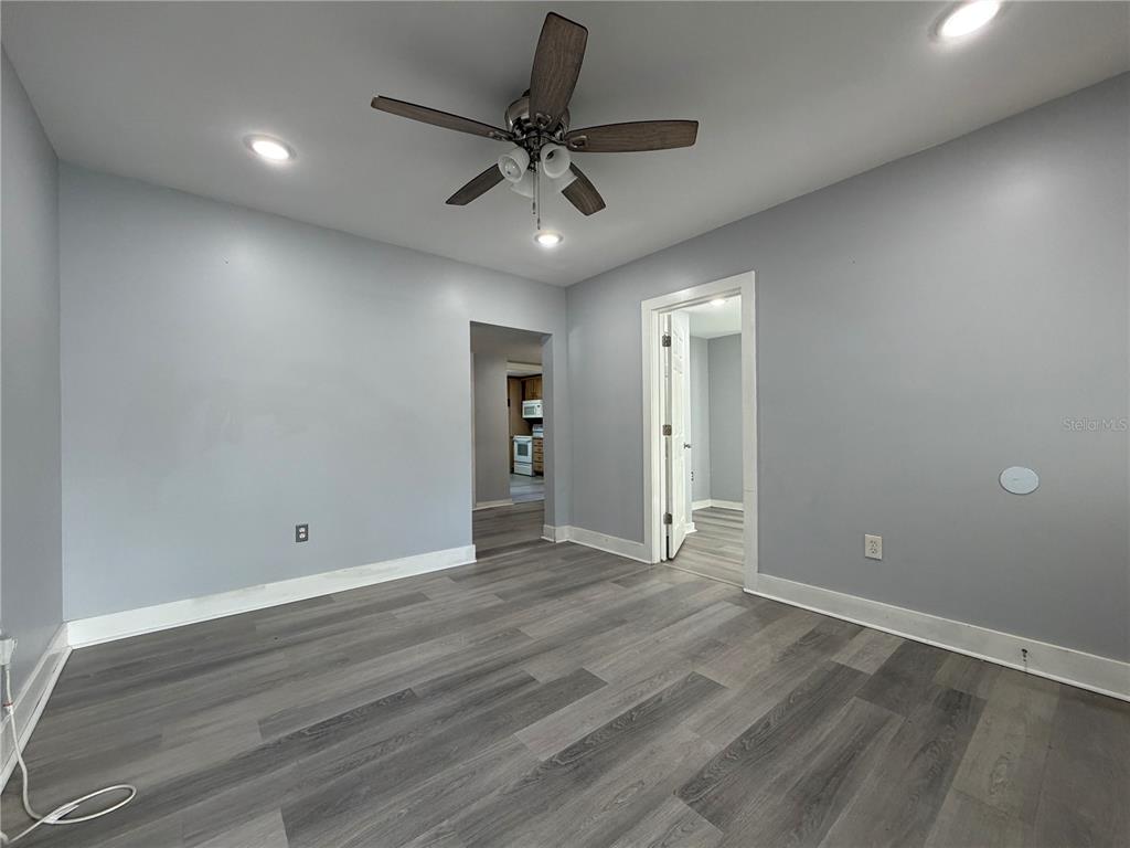 A room with gray walls, wood-look flooring, a ceiling fan, and a doorway to another room — 335 MAPLE STREET, DAYTONA BEACH, FL