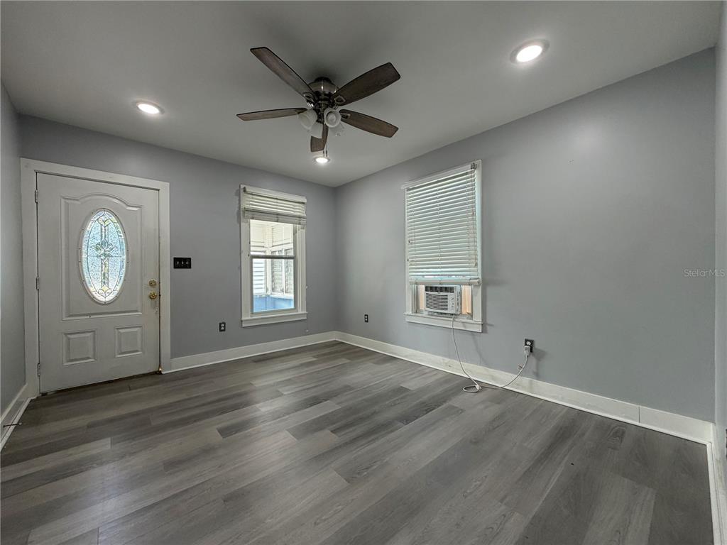 An empty room features gray walls, wood-look flooring, a ceiling fan, and two windows — 335 MAPLE STREET, DAYTONA BEACH, FL