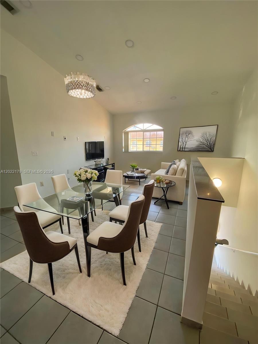 A dining area with a glass table and chairs sits adjacent to a living room — 7500 W 20th Ave # 202, Hialeah FL 33016, HIALEAH, FL