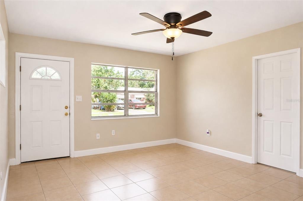 An empty room with beige walls, tile flooring, a ceiling fan, and two white doors — 821 14TH AVENUE NW, LARGO, FL