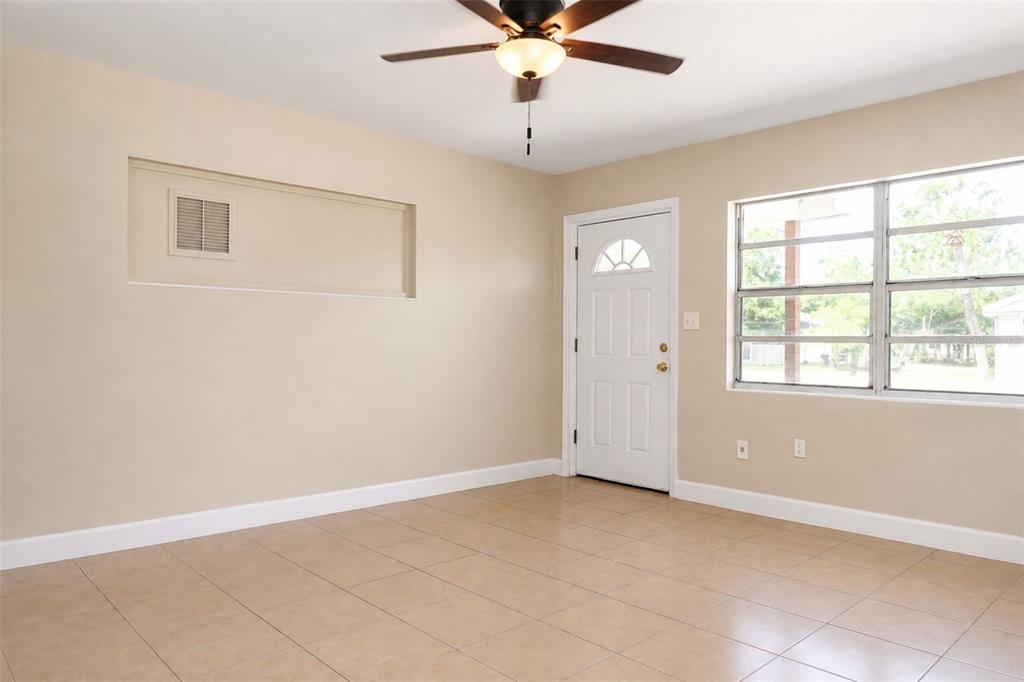 An empty room with beige walls, tile flooring, a ceiling fan, and a white door — 821 14TH AVENUE NW, LARGO, FL