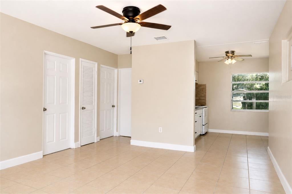 An interior view showing a living area with tile floors, ceiling fans, and a kitchen — 821 14TH AVENUE NW, LARGO, FL