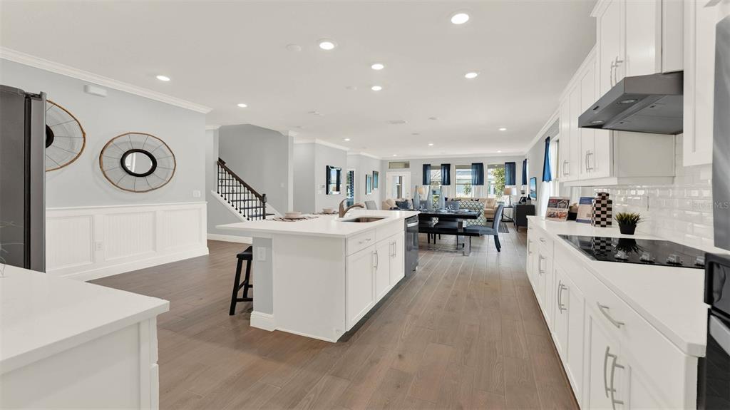 A modern kitchen with white cabinetry, a central island, and wood-look flooring — 11259 HOLLOW BAY DRIVE, WINTER GARDEN, FL