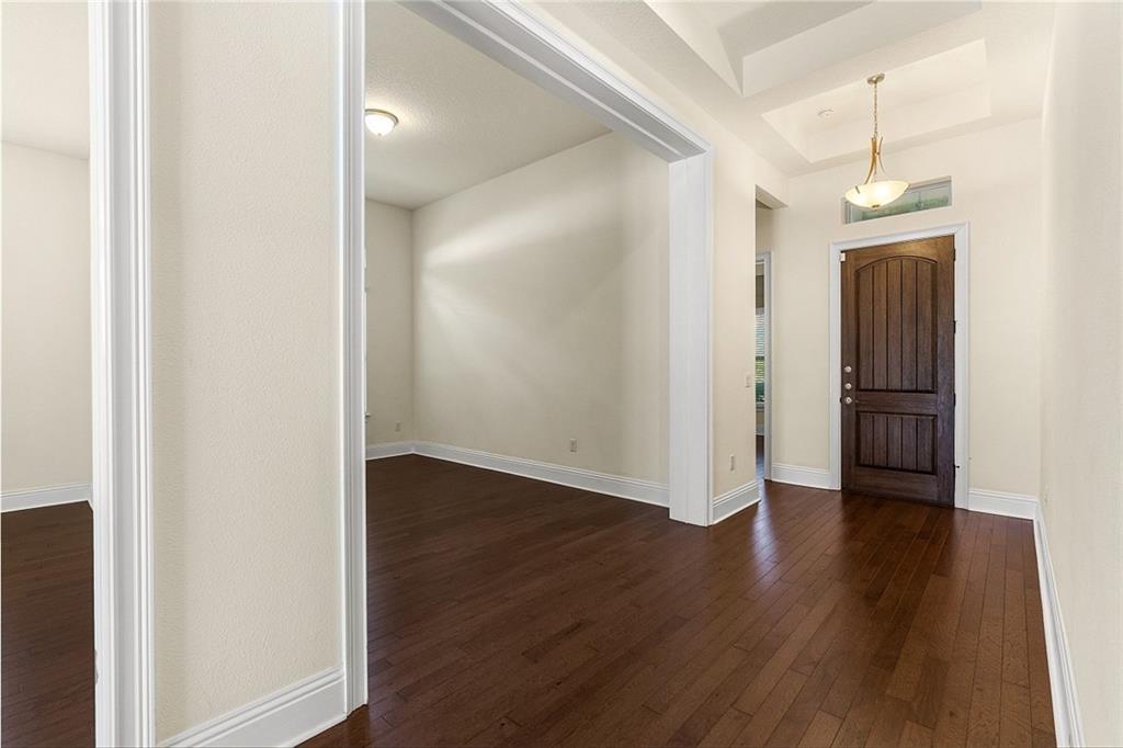 An entryway with dark hardwood floors, a wooden front door, and an adjacent open room — ORLANDO, FL