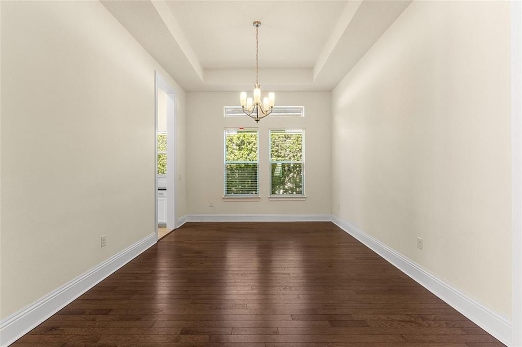 An empty dining room features dark hardwood floors, a tray ceiling, and a chandelier — ORLANDO, FL