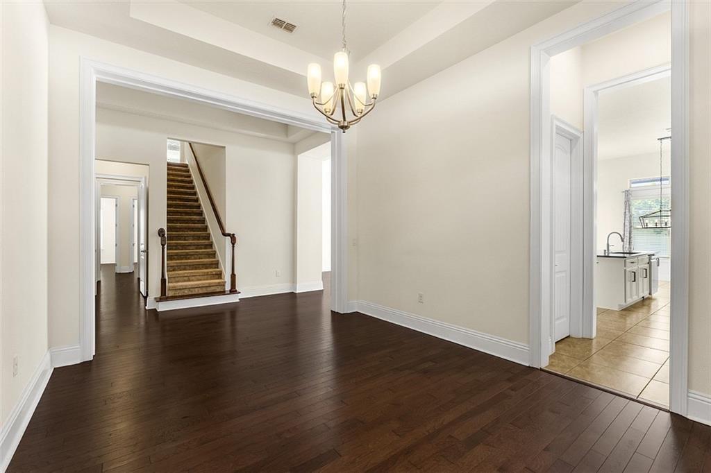 A dining room with dark hardwood floors, a chandelier, and a view of a staircase — ORLANDO, FL