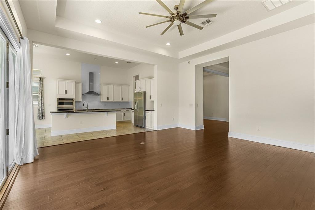 A spacious living room with hardwood floors opens into a kitchen with white cabinetry — ORLANDO, FL