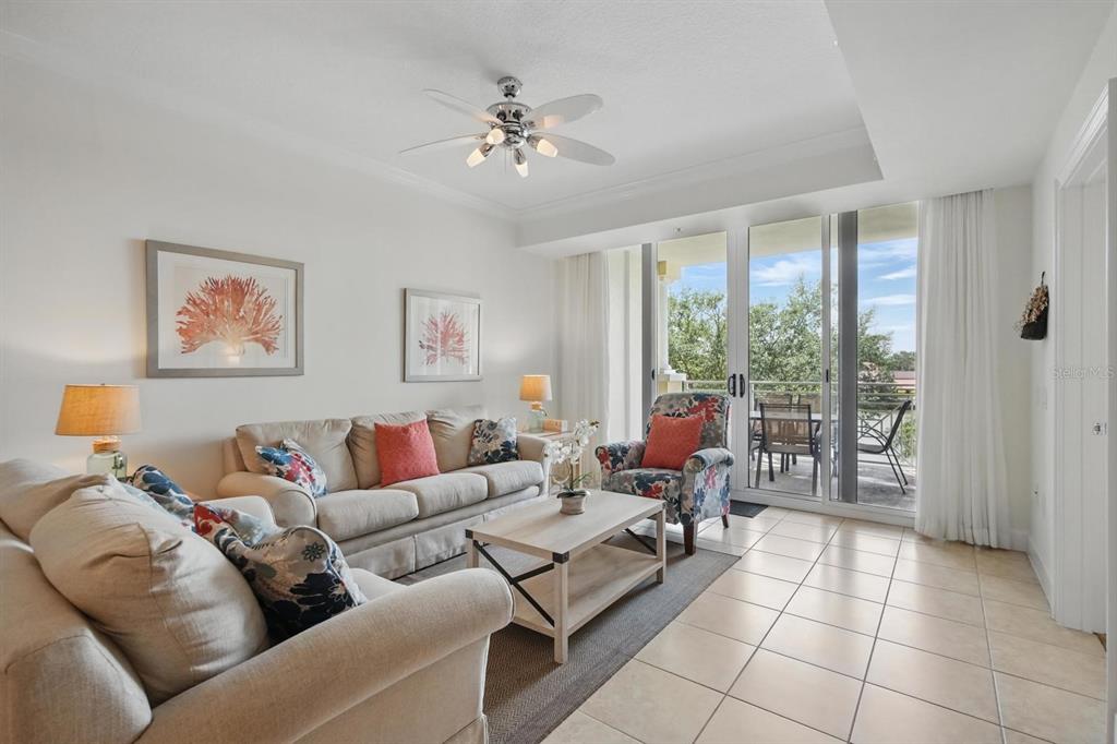 A living room features a beige sofa, patterned armchair, coffee table, and sliding glass balcony doors — 102 YACHT HARBOR DRIVE UNIT 263, PALM COAST, FL