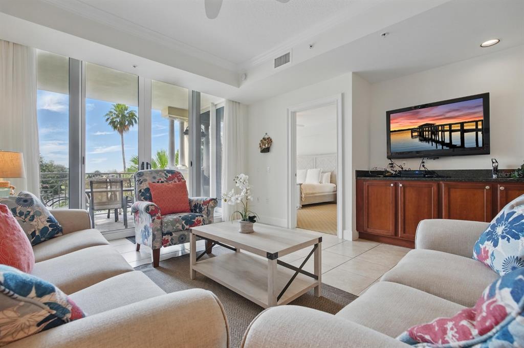 A living room with beige sofas, a floral armchair, a coffee table, and a balcony view — 102 YACHT HARBOR DRIVE UNIT 263, PALM COAST, FL