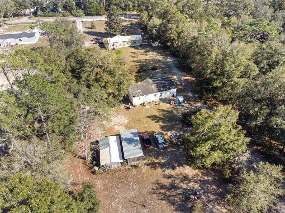 An aerial view shows two houses and a shed on a large, wooded residential lot — 3230 SW 189th Avenue, FL 34432, FL