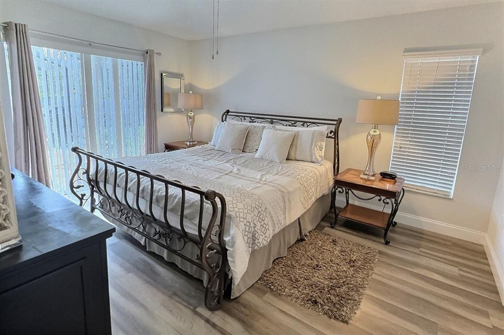 A bedroom features a metal bed frame, two nightstands with lamps, and wood-look flooring — 1005 LAKE BERKLEY DRIVE, KISSIMMEE, FL