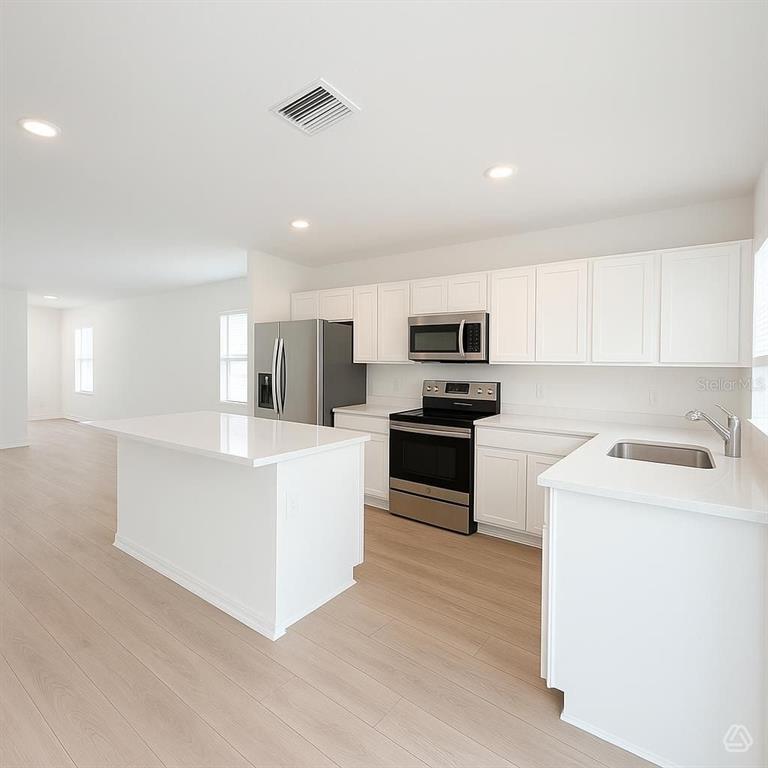 A modern kitchen features white cabinets, stainless steel appliances, and a central island — 13020 SASSAFRAS TRAIL, PARRISH, FL