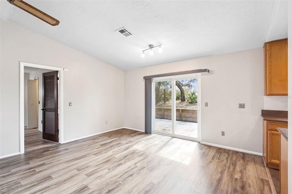 An empty dining area features wood-look flooring, a sliding glass door, and a ceiling light — 501 ANTOINETTE STREET, DELTONA, FL