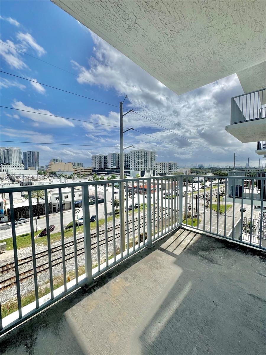 A concrete balcony with a metal railing overlooks a street, railroad tracks, and city buildings — 140 S Dixie Hwy # 513, Hollywood FL 33020, HOLLYWOOD, FL