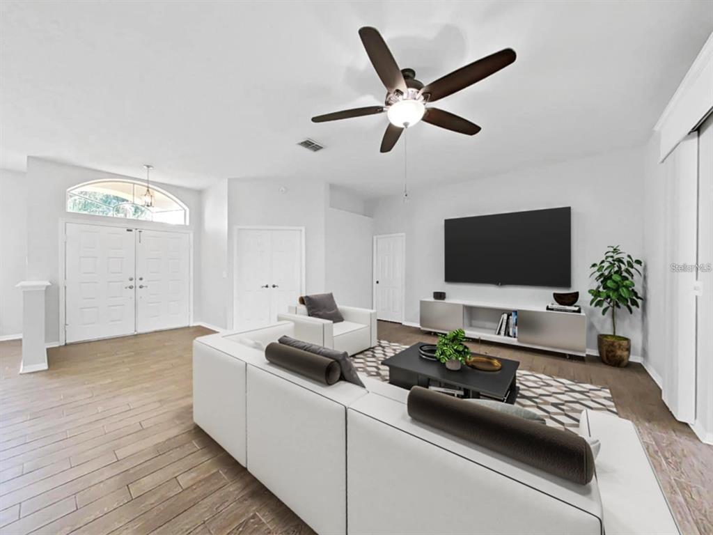A living room features white walls, wood-look tile flooring, a large sectional sofa, and television — 3307 KILMER PLACE, PLANT CITY, FL