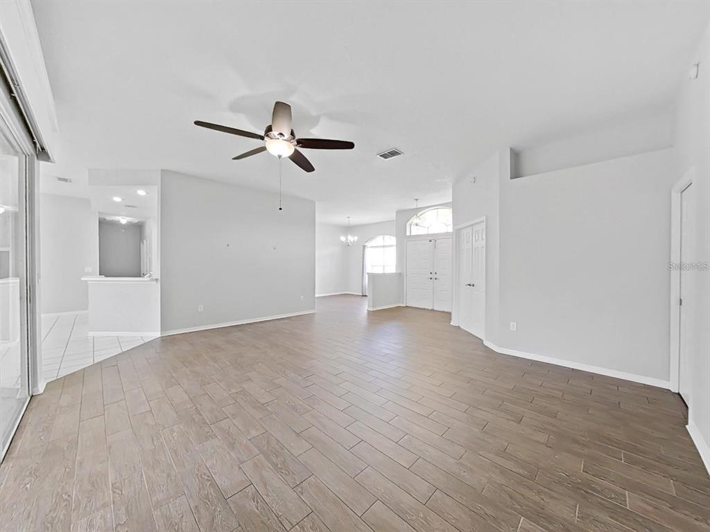 An open-concept living area features light gray walls, wood-look tile flooring, and a ceiling fan — 3307 KILMER PLACE, PLANT CITY, FL