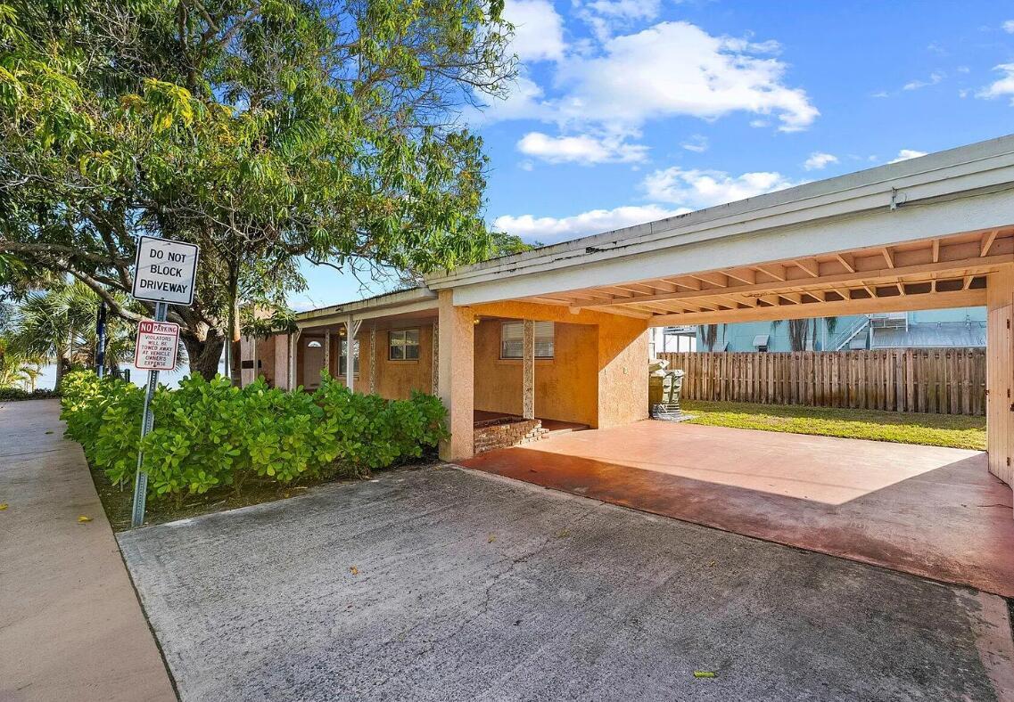 A concrete driveway leads to a covered carport attached to a single-story stucco house — 101 S Colorado Avenue, Stuart FL 34994, STUART, FL