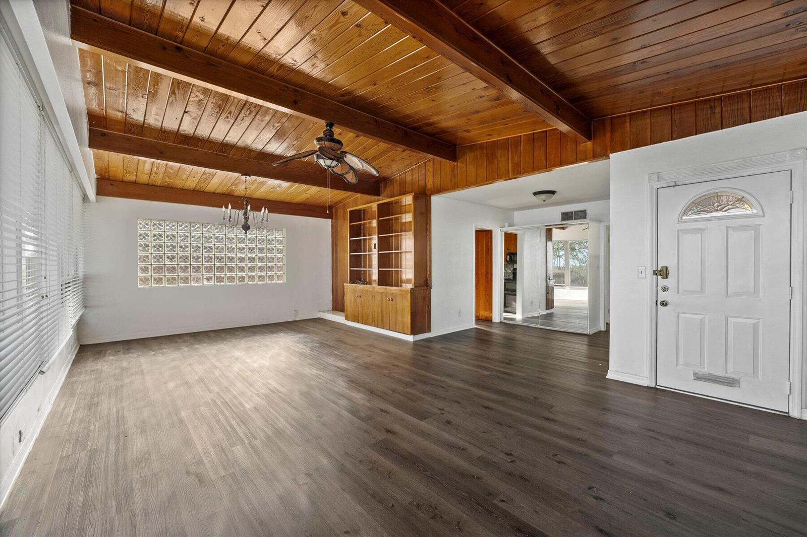An empty living room features a wood-paneled vaulted ceiling, glass block window, and dark flooring — 101 S Colorado Avenue, Stuart FL 34994, STUART, FL