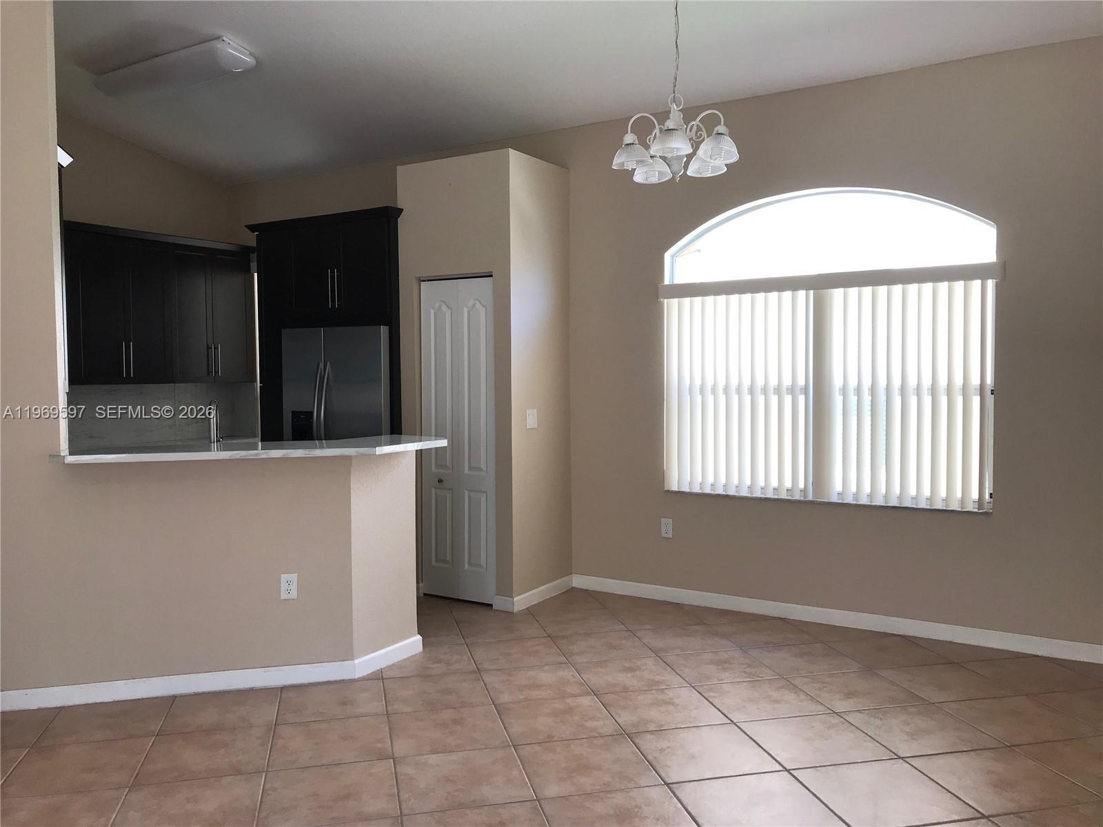 A kitchen with dark cabinets and a breakfast bar opens into a dining area — 3748 NE 9th Ct, Homestead FL 33033, HOMESTEAD, FL