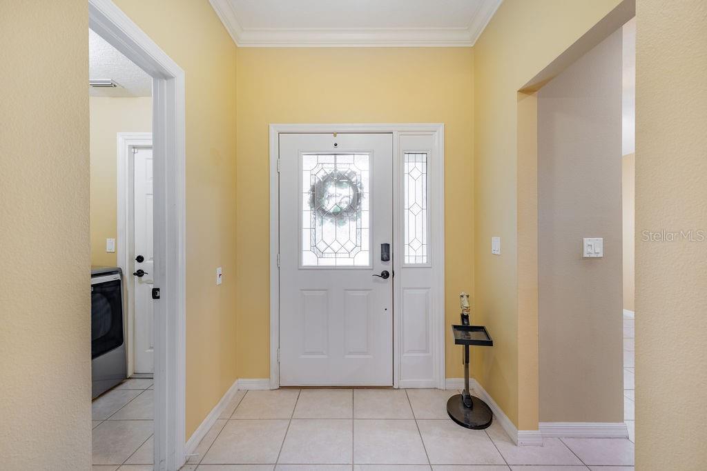 A tiled entryway features a white front door with a decorative glass insert and sidelight — 6116 ARMADA STREET, TAVARES, FL
