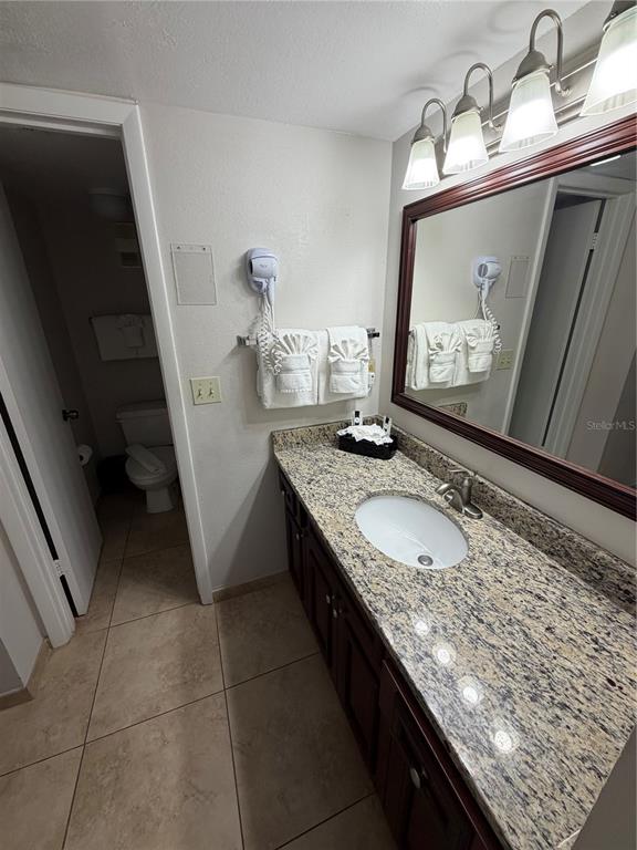 A bathroom features a granite vanity, dark wood cabinets, a mirror, and a separate toilet area — 6403 PARC CORNICHE DRIVE UNIT 4305, ORLANDO, FL