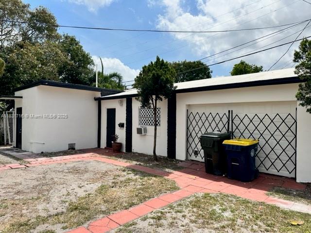 A white single-story house features a garage with a metal gate and two trash bins — 42 SE 10th Ter, Dania Beach FL 33004, DANIA BEACH, FL