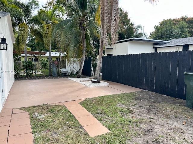 A backyard features a concrete patio, a black wooden fence, and a palm tree — 42 SE 10th Ter, Dania Beach FL 33004, DANIA BEACH, FL