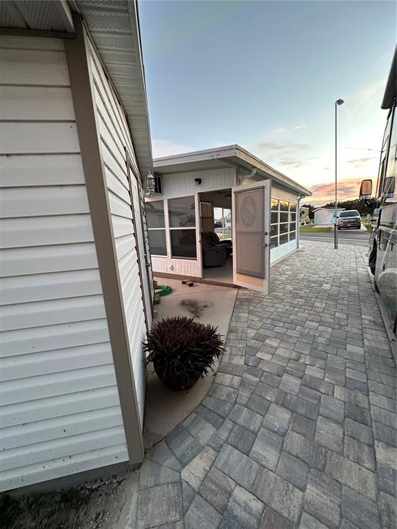 A white siding structure features a screened-in porch with a paved walkway and driveway — 46900 BERMONT ROAD UNIT 310, PUNTA GORDA, FL