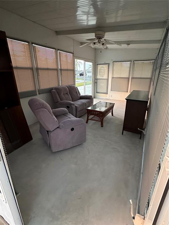 A sunroom features a ceiling fan, gray recliner, loveseat, coffee table, and large windows — 46900 BERMONT ROAD UNIT 310, PUNTA GORDA, FL