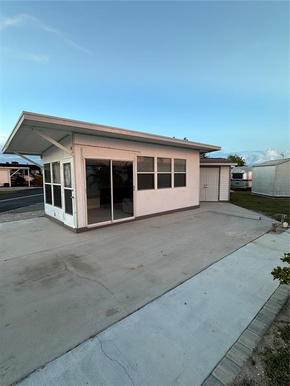 A white mobile home features a large concrete patio and a glass sliding door entrance — 46900 BERMONT ROAD UNIT 310, PUNTA GORDA, FL