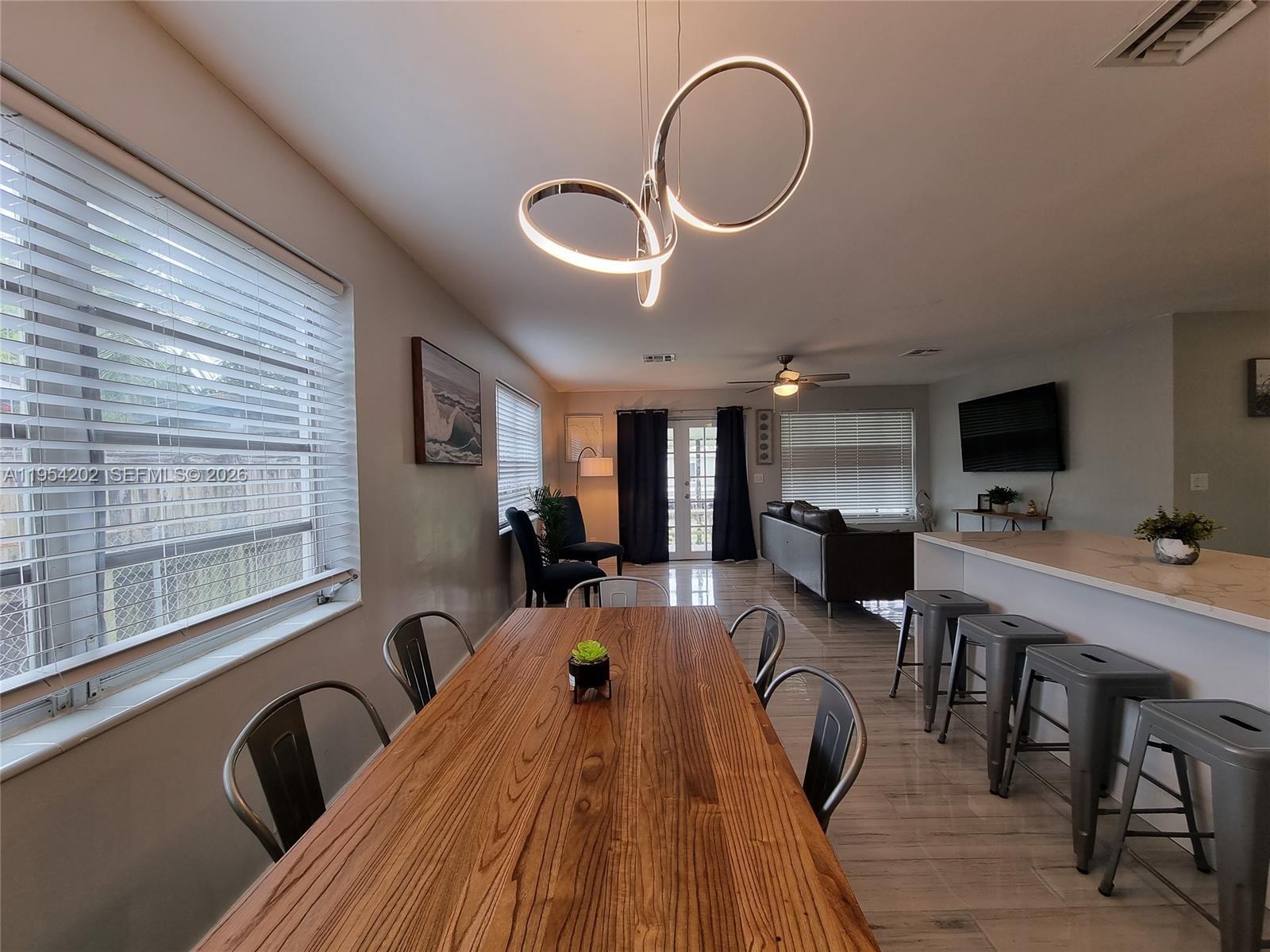 A dining area with a wooden table and metal chairs opens into a living room — 4740 SW 43rd Ave, Dania Beach FL 33314, DANIA BEACH, FL