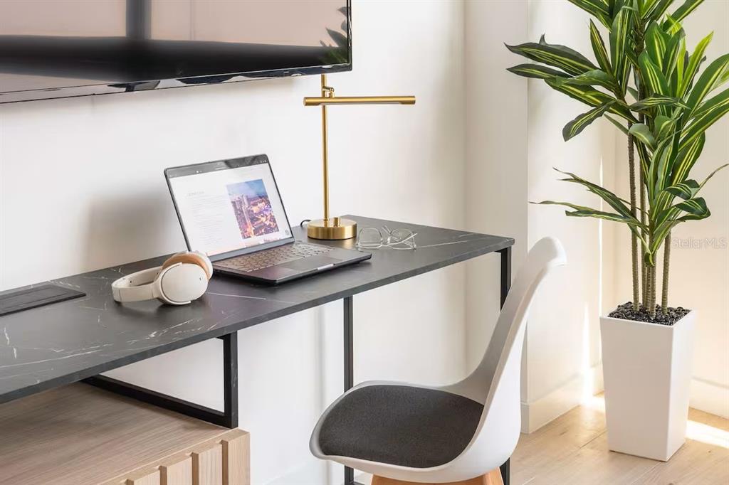 A modern home office desk with a laptop, lamp, and chair next to a potted plant — 225 N MIAMI AVENUE UNIT 1407, MIAMI, FL