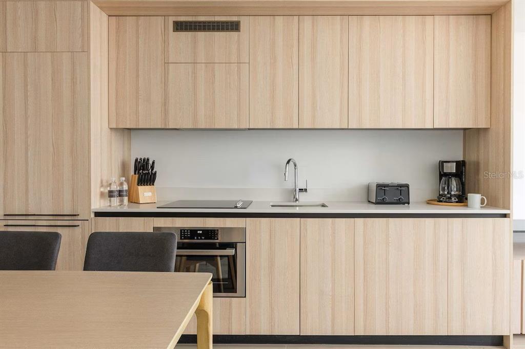 A modern kitchen features light wood cabinetry, a white countertop, and integrated stainless steel appliances — 225 N MIAMI AVENUE UNIT 1407, MIAMI, FL