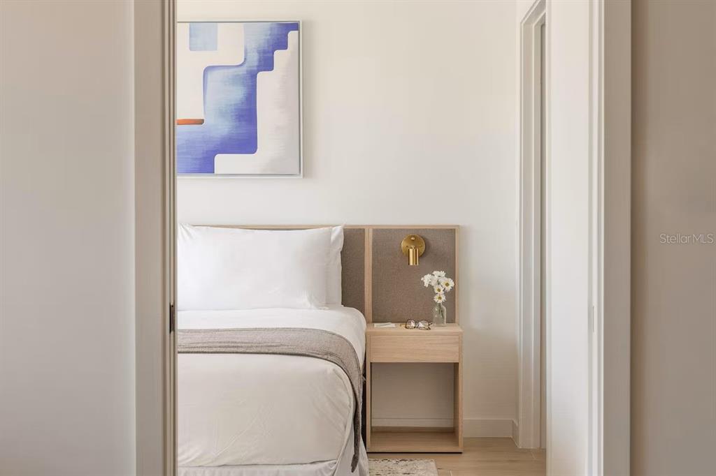 A bedroom features a bed with a light wood headboard, a matching nightstand, and abstract art — 225 N MIAMI AVENUE UNIT 1407, MIAMI, FL