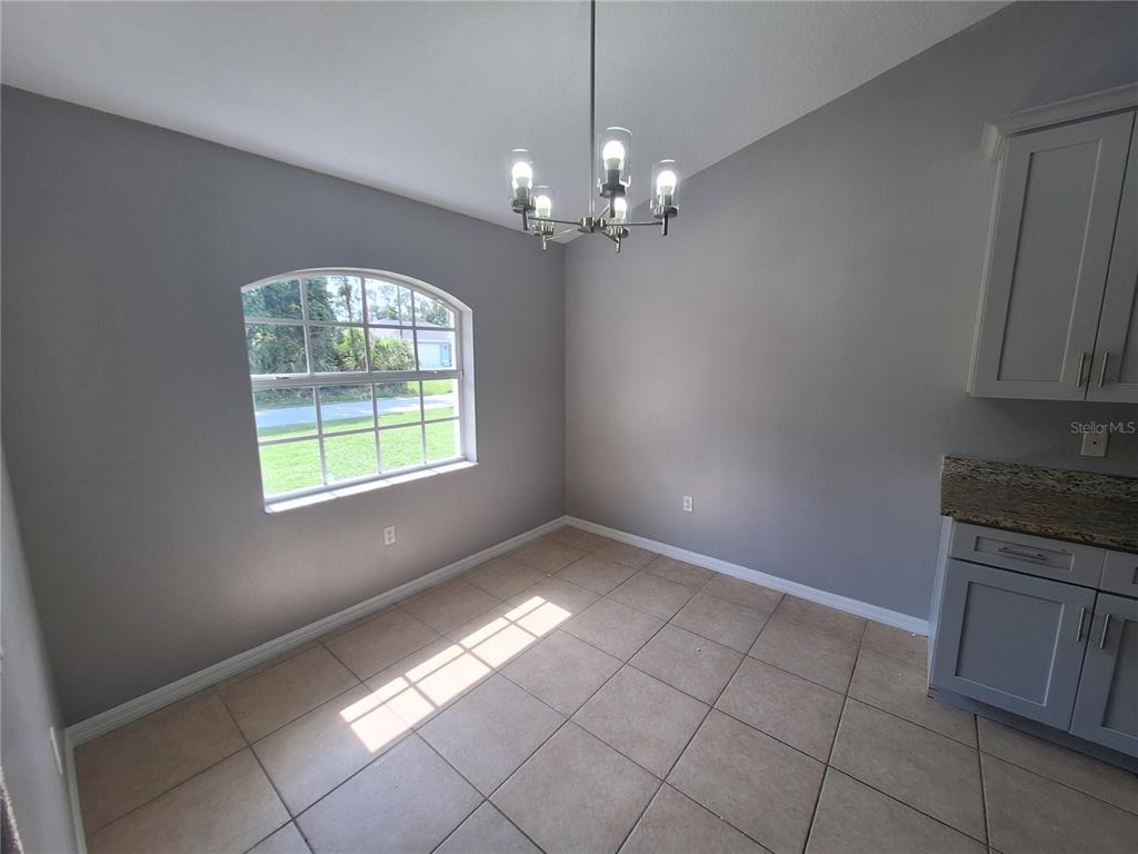 A dining area features gray walls, tile flooring, an arched window, and a chandelier — 1220 WAYCROSS STREET, NORTH PORT, FL