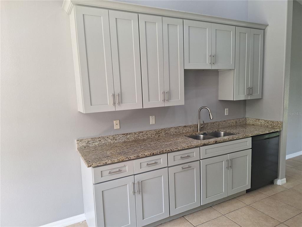 A kitchen features light gray cabinets, granite countertops, a stainless steel sink, and dark appliances — 1220 WAYCROSS STREET, NORTH PORT, FL