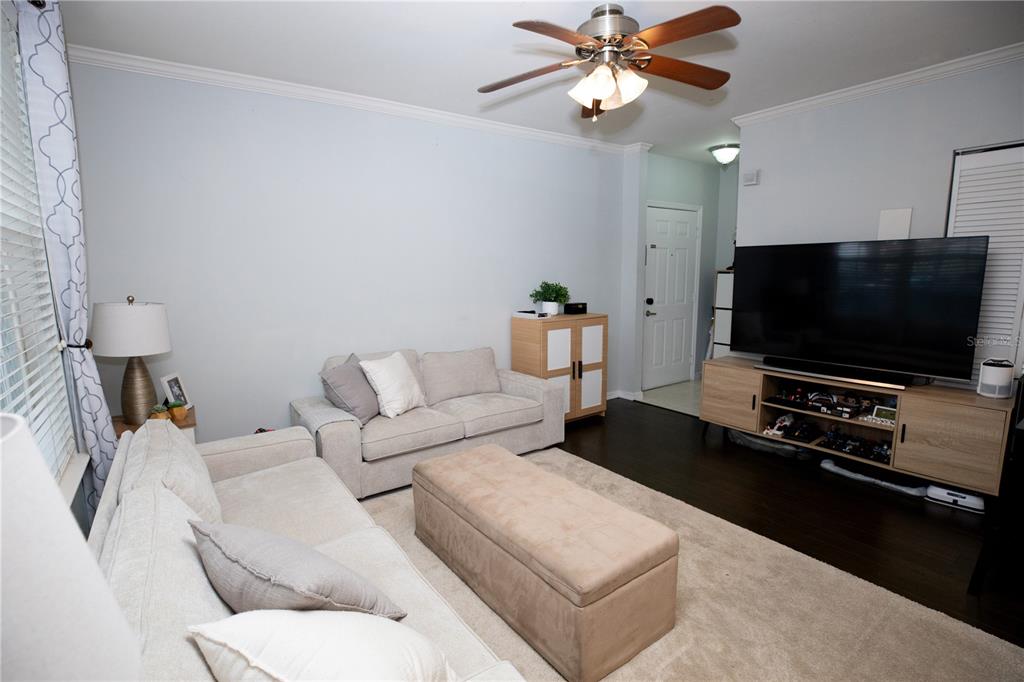 A living room features a beige sofa, matching loveseat, ottoman, and a large television console — 1020 SIENA PARK BOULEVARD W UNIT # 103, CELEBRATION, FL