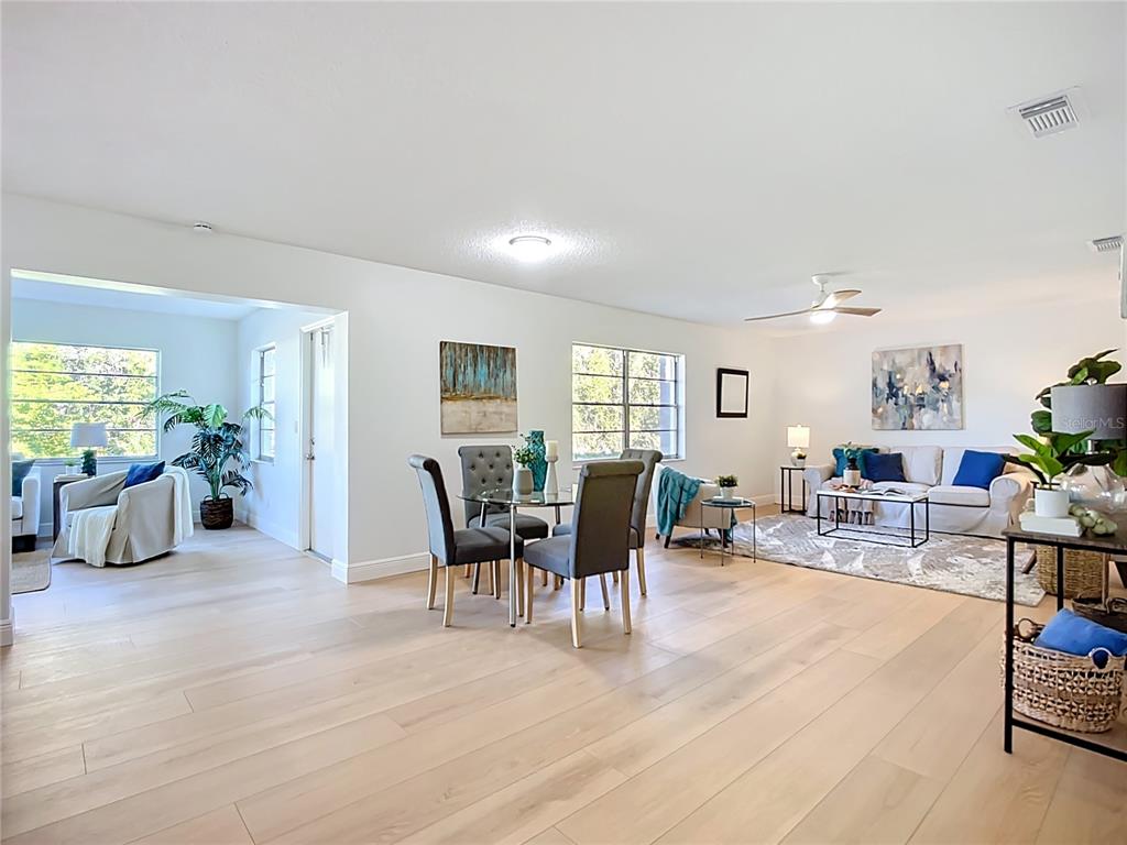 A bright, open-concept living and dining area features light wood flooring and neutral walls — 2014 HAMPSTEAD CIRCLE, SUN CITY CENTER, FL